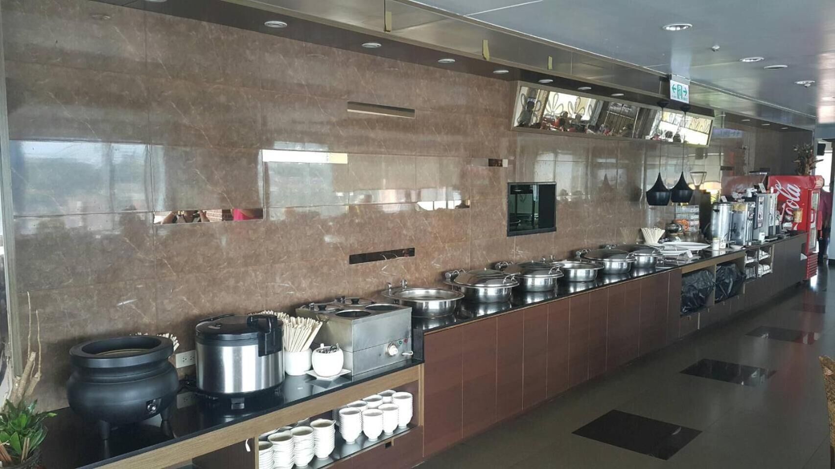 Een buffetopstelling met diverse opsLAGS stations, RVS-potten en een Coca-Cola koelkast.