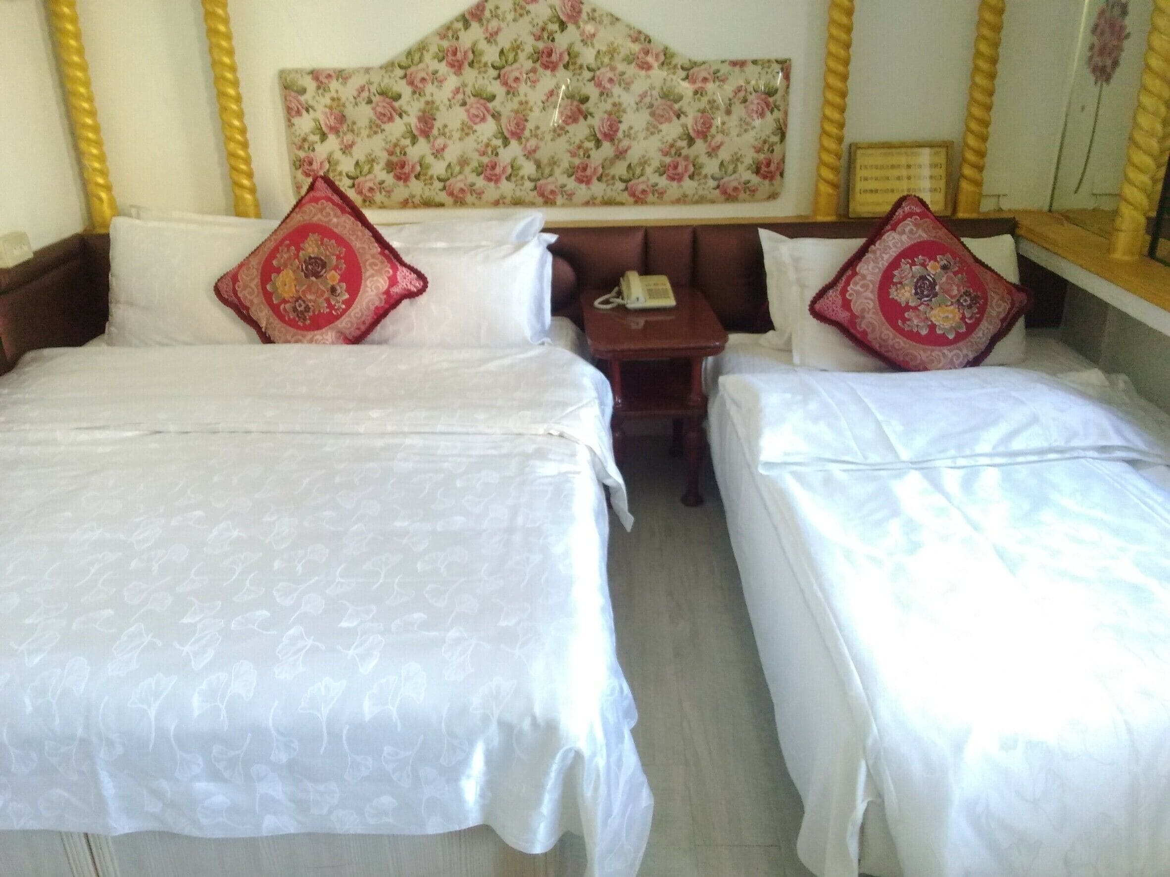 Habitación de hotel con dos camas individuales, una mesita y un teléfono.