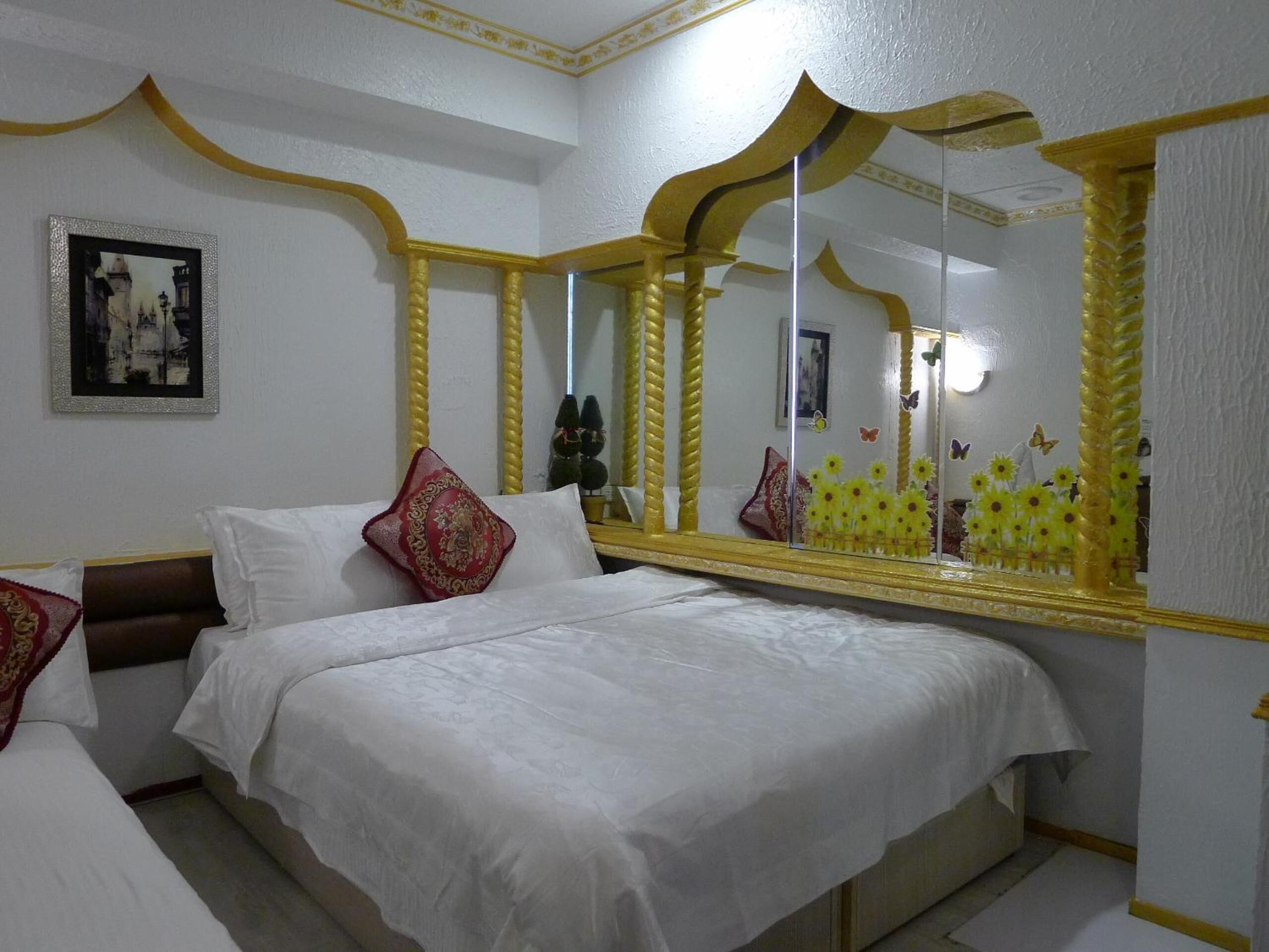 A hotel room with a large bed, a mirror, and a framed picture on the wall.
