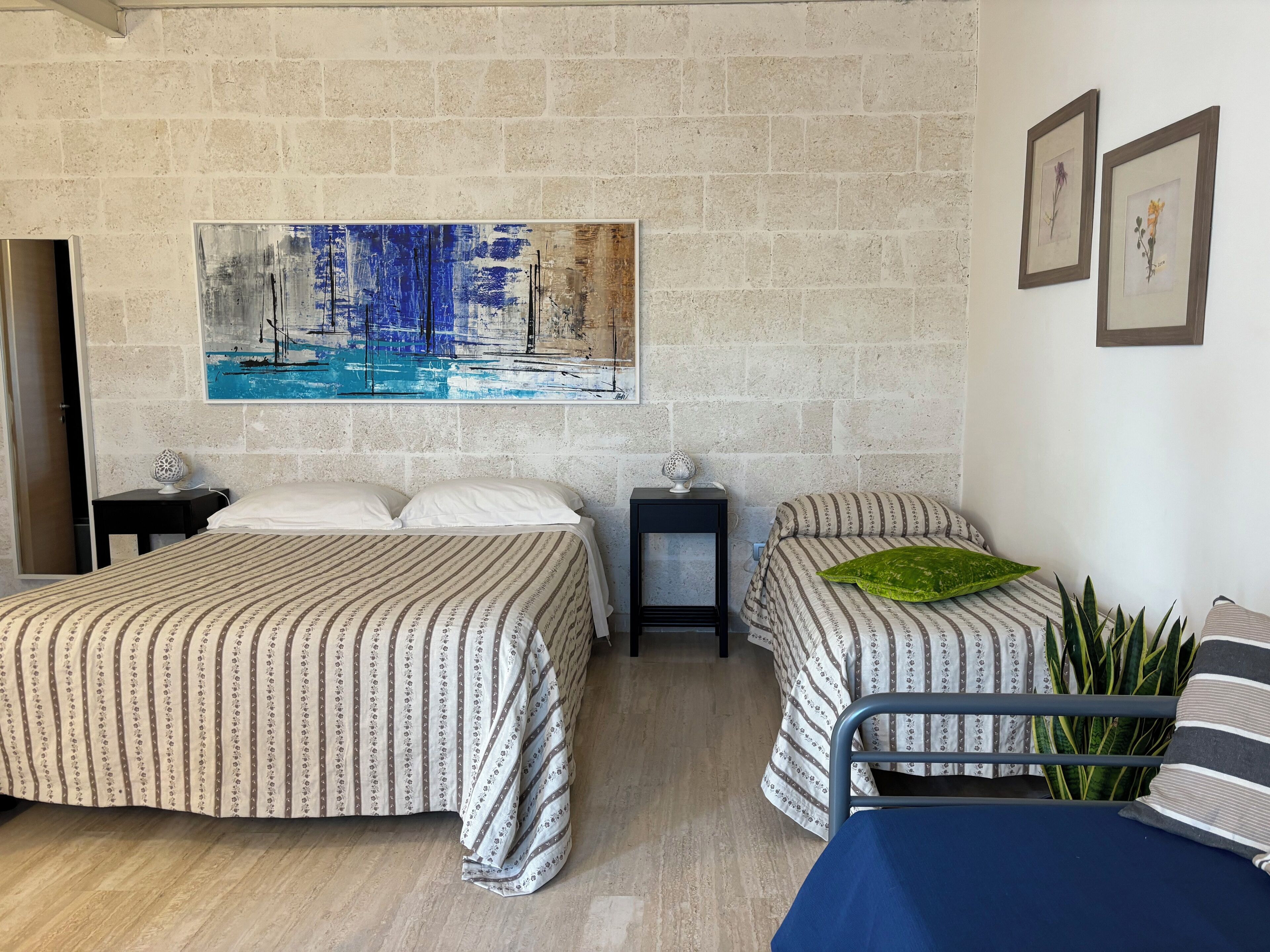Habitación de hotel con dos camas, una mesita pequeña, una silla y un cuadro grande en la pared.