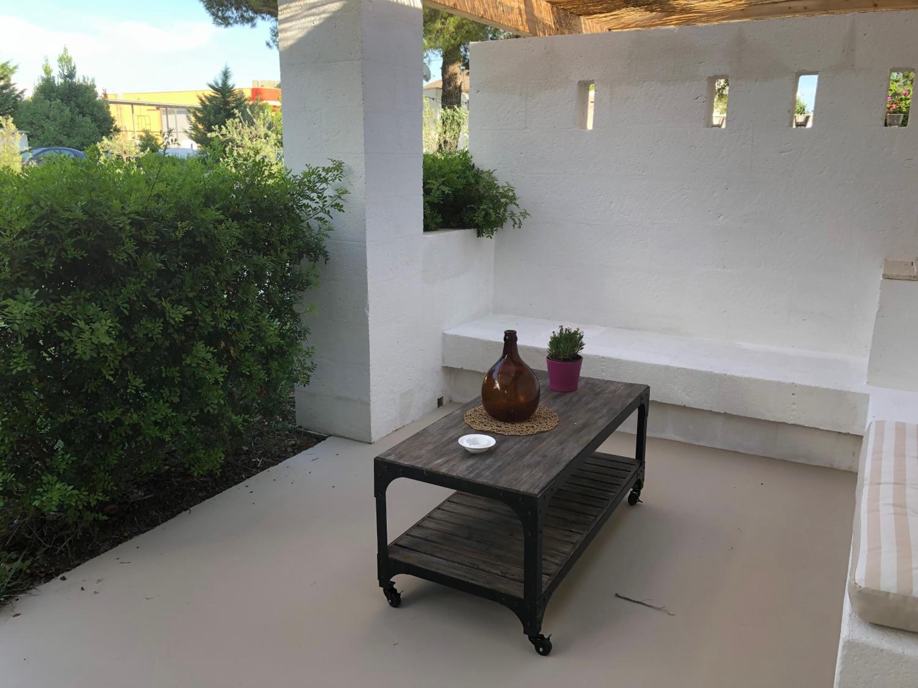 Un espace extérieur aménagé en terrasse, avec une table en bois, un vase et une plante en pot.