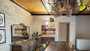 A dining area with a wooden table and chairs, a brick wall, and a hanging light fixture.