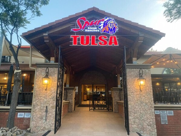 En byggnadsingång med en skylt som visar ”Spur Steak Ranches” och ”TULSA”.