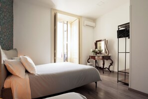 A bedroom with a bed, a dresser, a mirror, and an open door leading to another room. - B&B Università (Catania)
