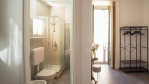A modern bathroom with a toilet, shower, and glass-enclosed shower stall. - B&B Università (Catania)