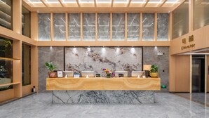 A reception desk with a marble top, a large wall-mounted screen, and a wooden panel design. - Guangzhou BoYi Hotel (Guangzhou)
