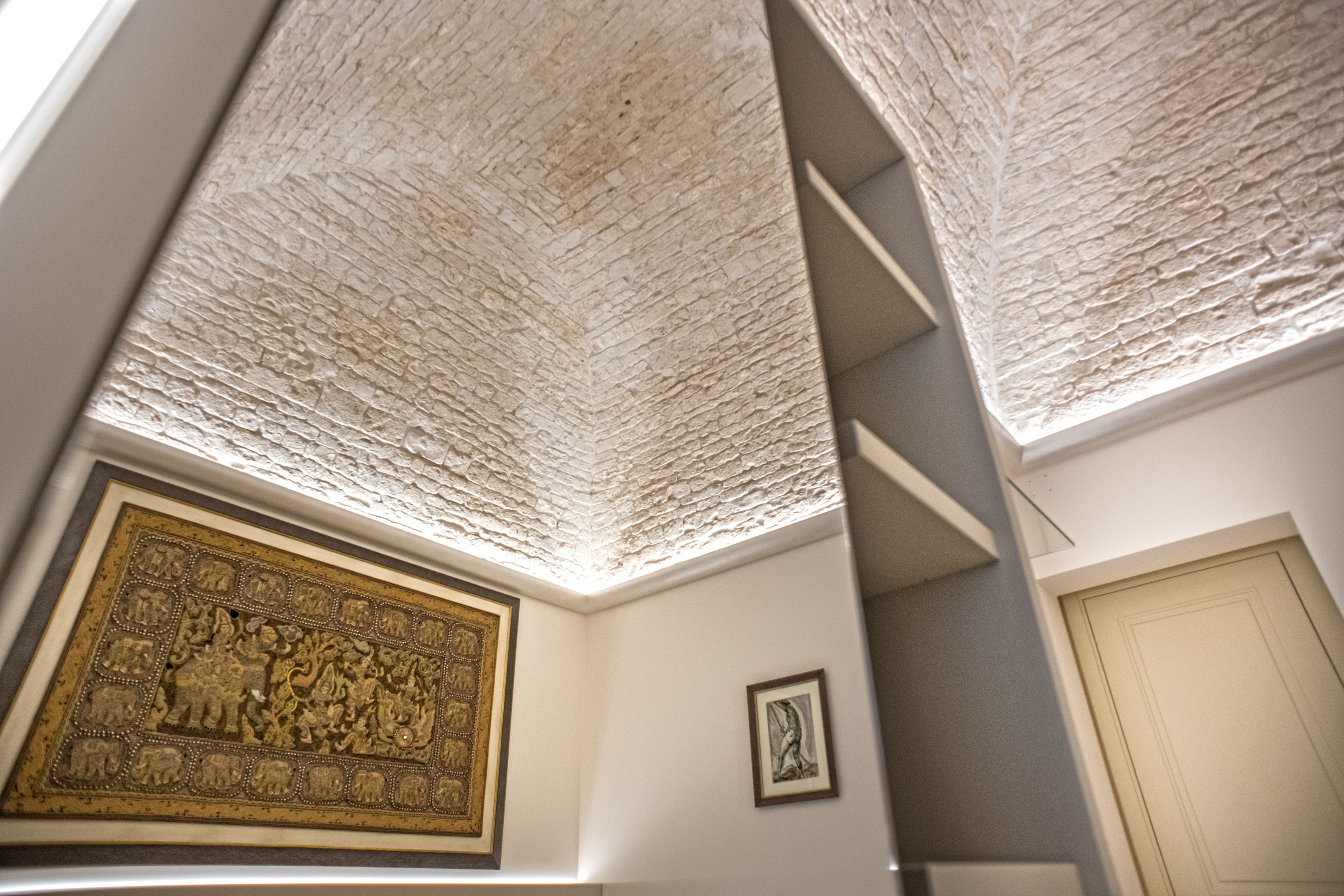 Una habitación con techo texturizado, una obra de arte grande enmarco, una puerta y una escalera.