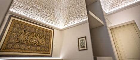 Una habitación con techo texturizado, una obra de arte grande enmarco, una puerta y una escalera.