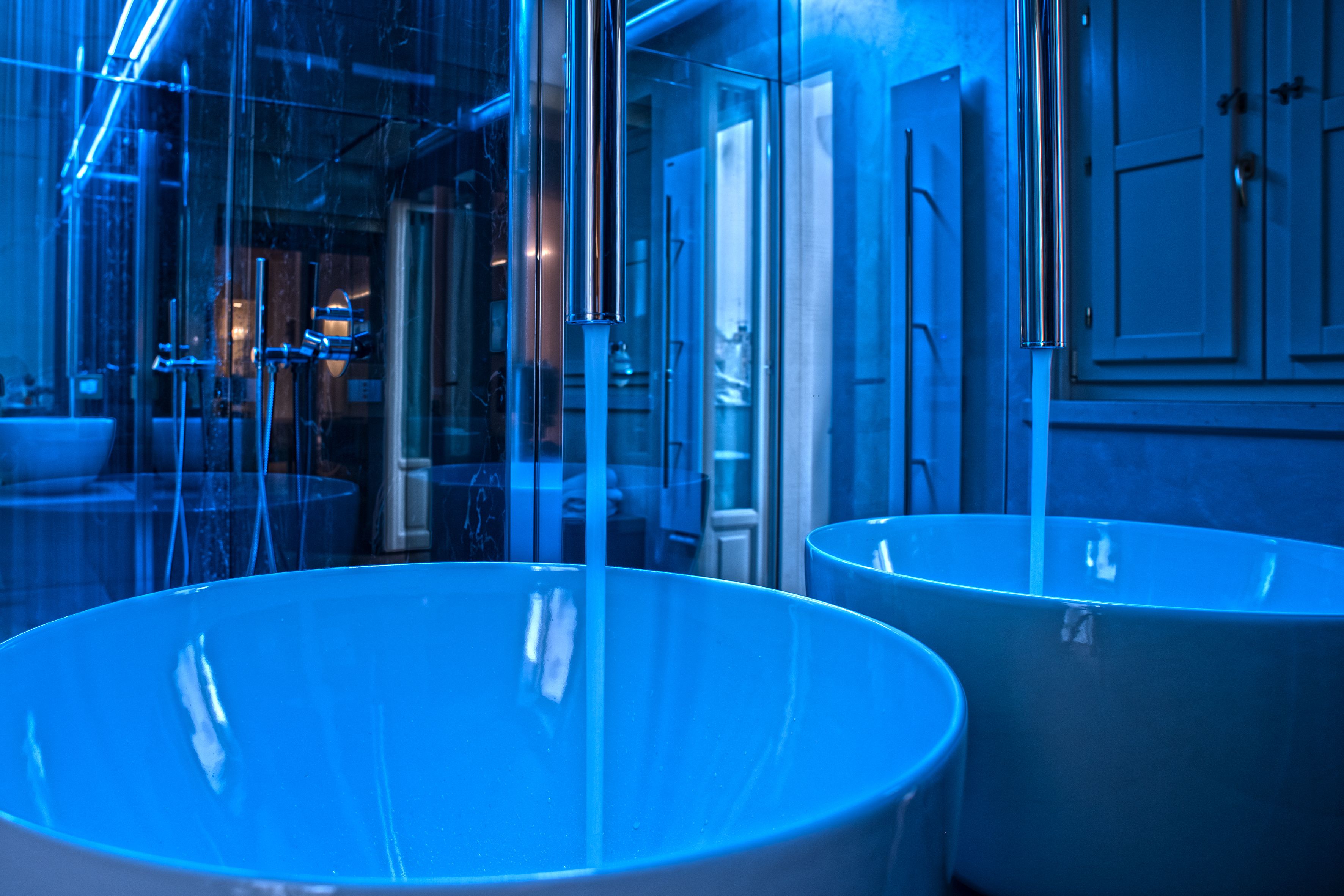 Un baño moderno con lavamanos grandes y redondos y separadores de vidrio.