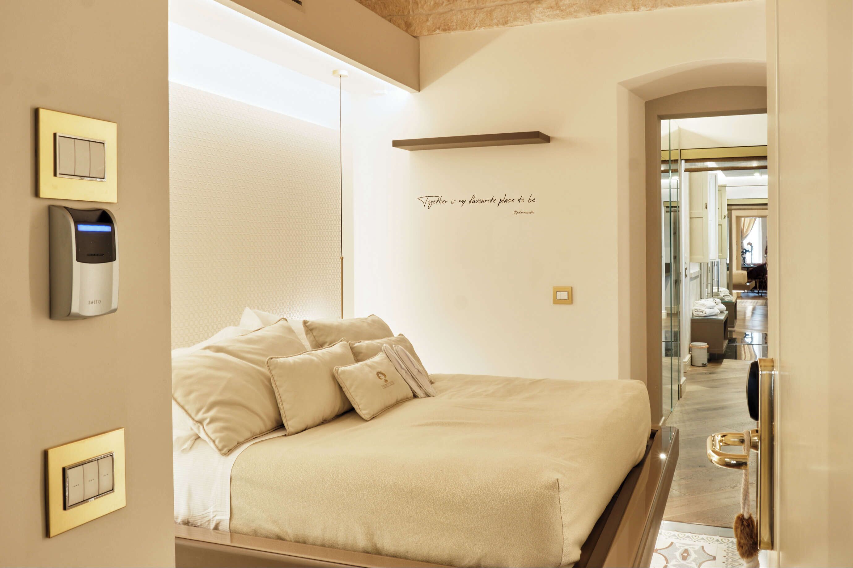 Una habitación de hotel con una cama grande, controles junto a la cama, una mesita de noche y un espejo.