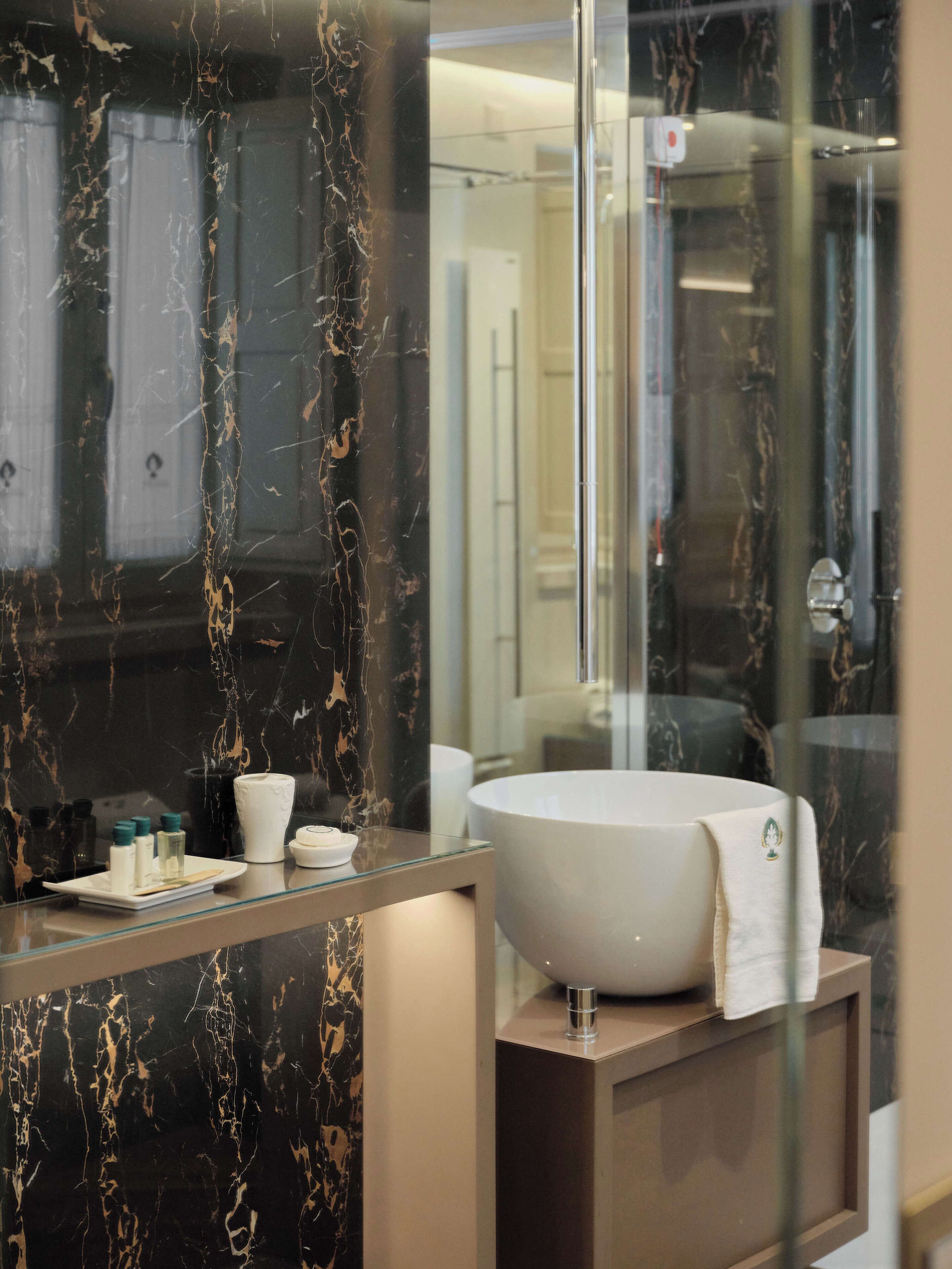 A bathroom with a large, round bathtub, a glass countertop, and a marble backsplash.