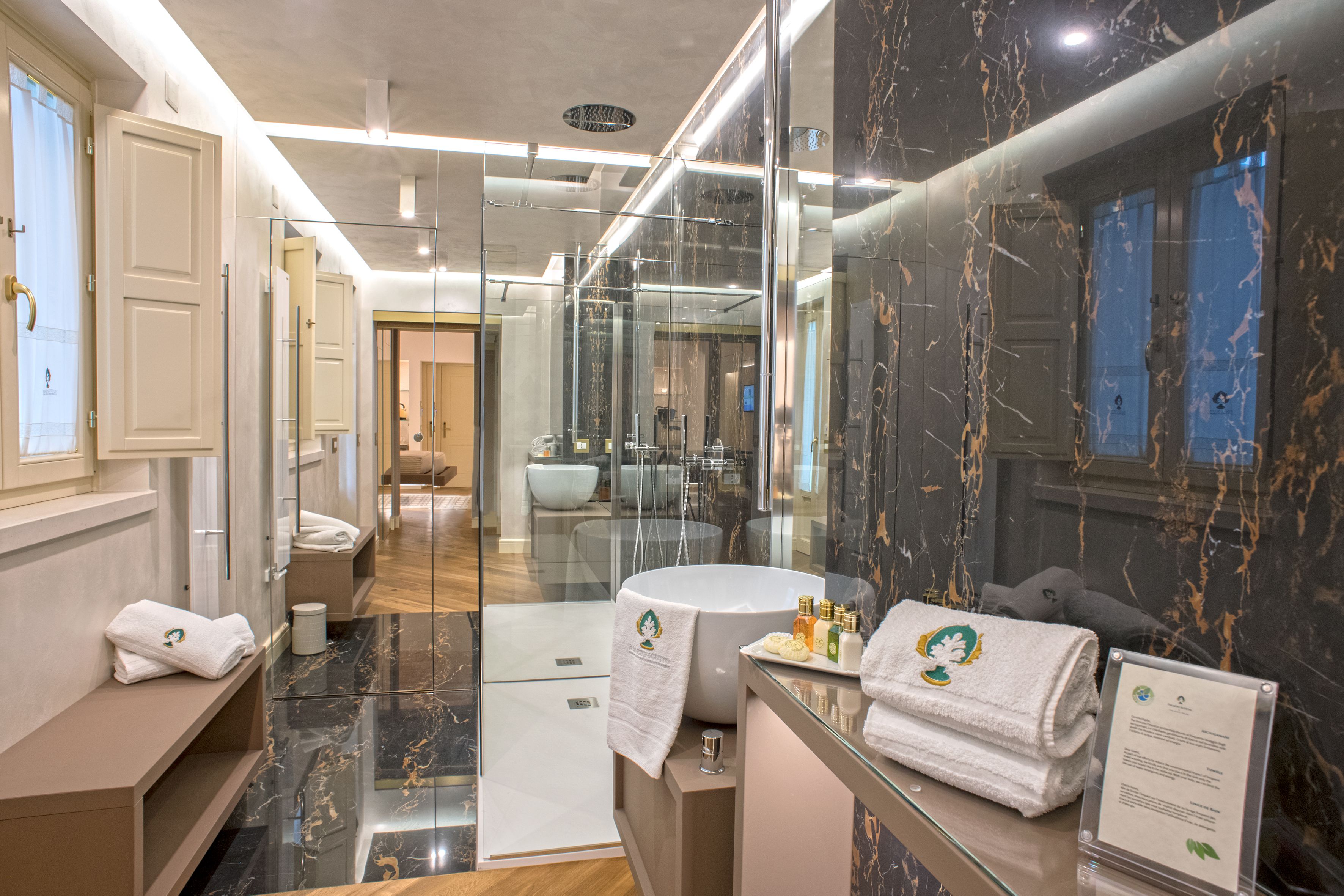 A modern bathroom with a marble floor, a glass-enclosed shower, and a vanity with a mirror.