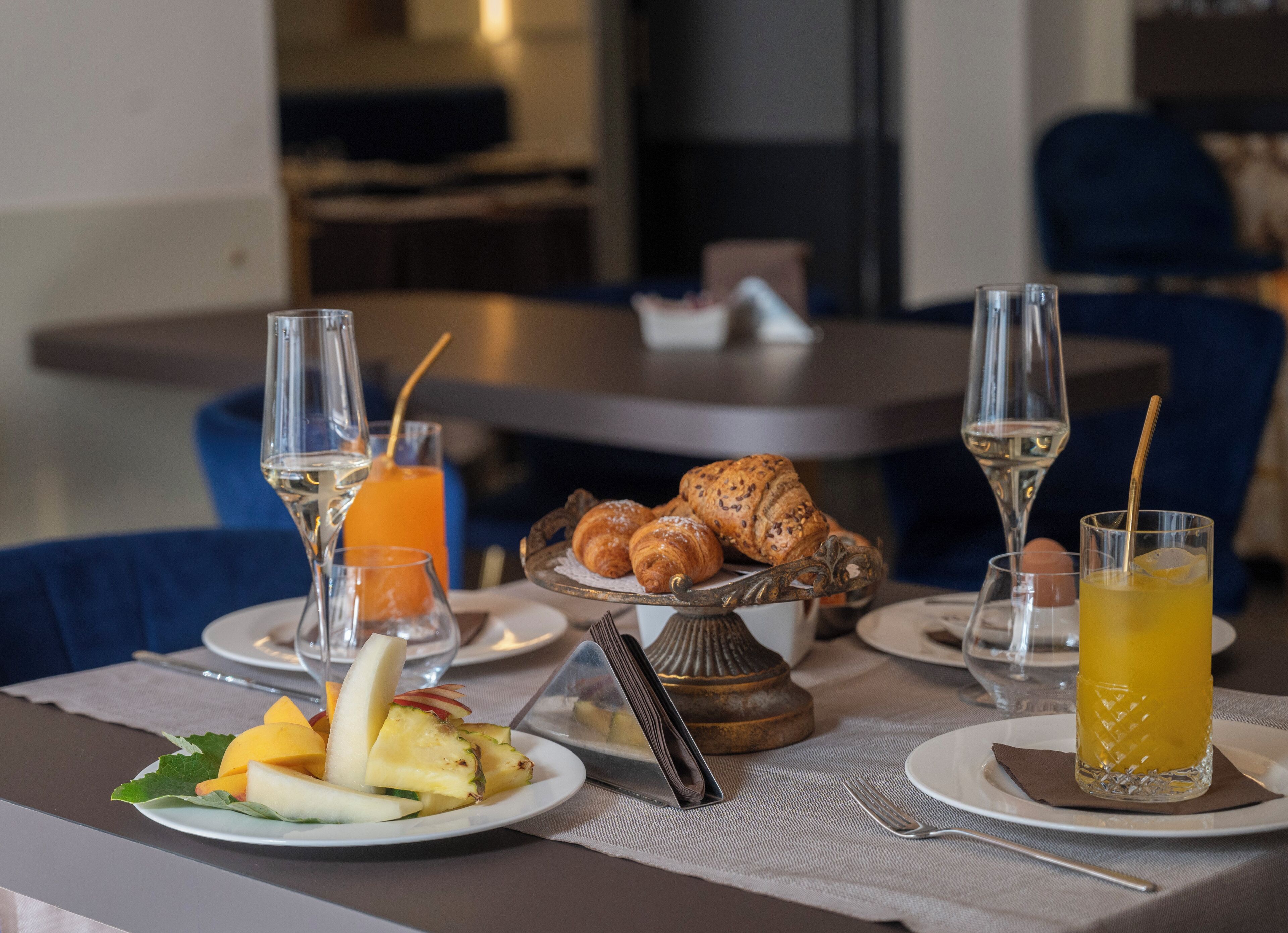 A breakfast setting with croissants, fruit, and beverages on a table.