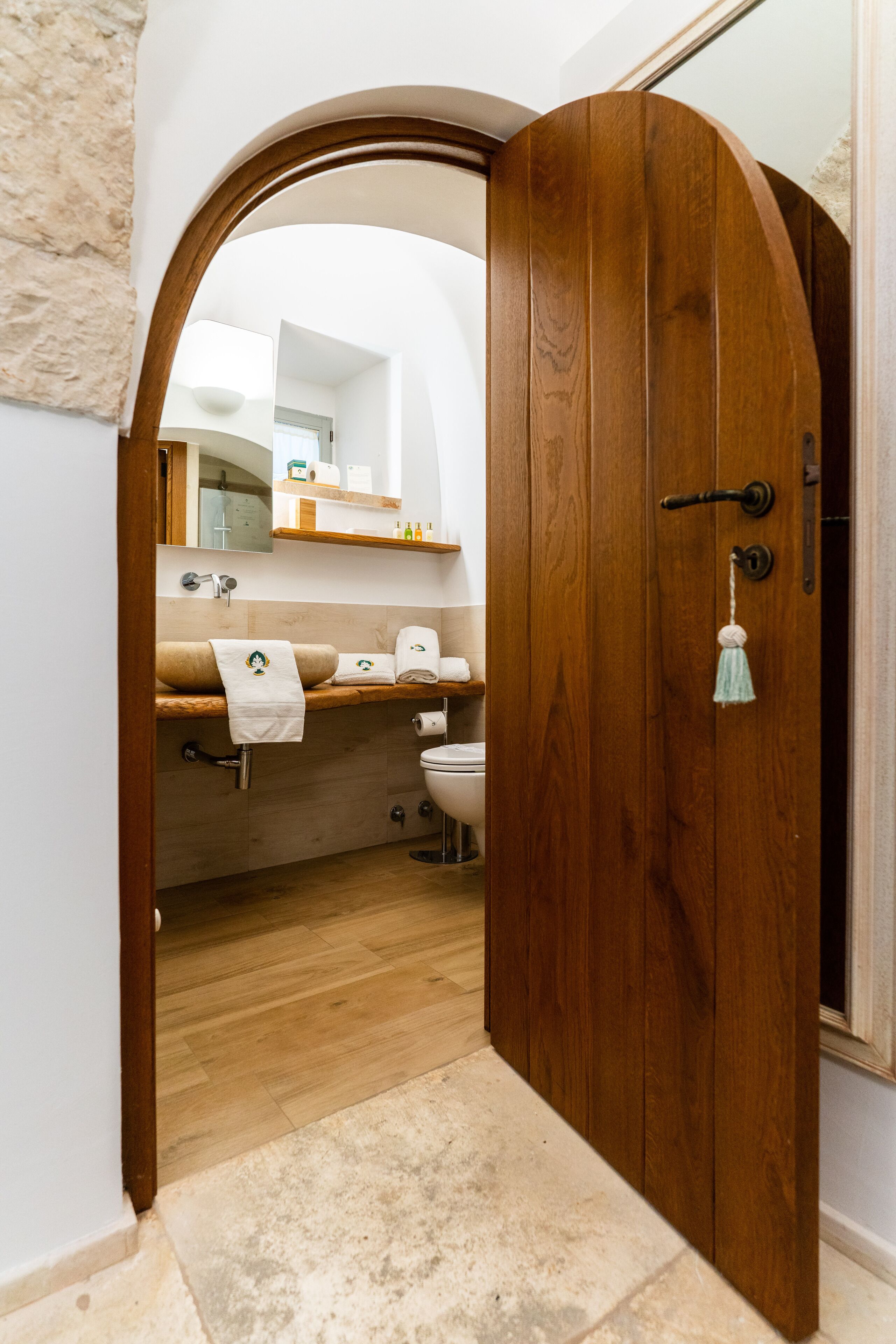 Eine Holztür zu einem Badezimmer mit Waschtisch, Handtuch und Toilette.