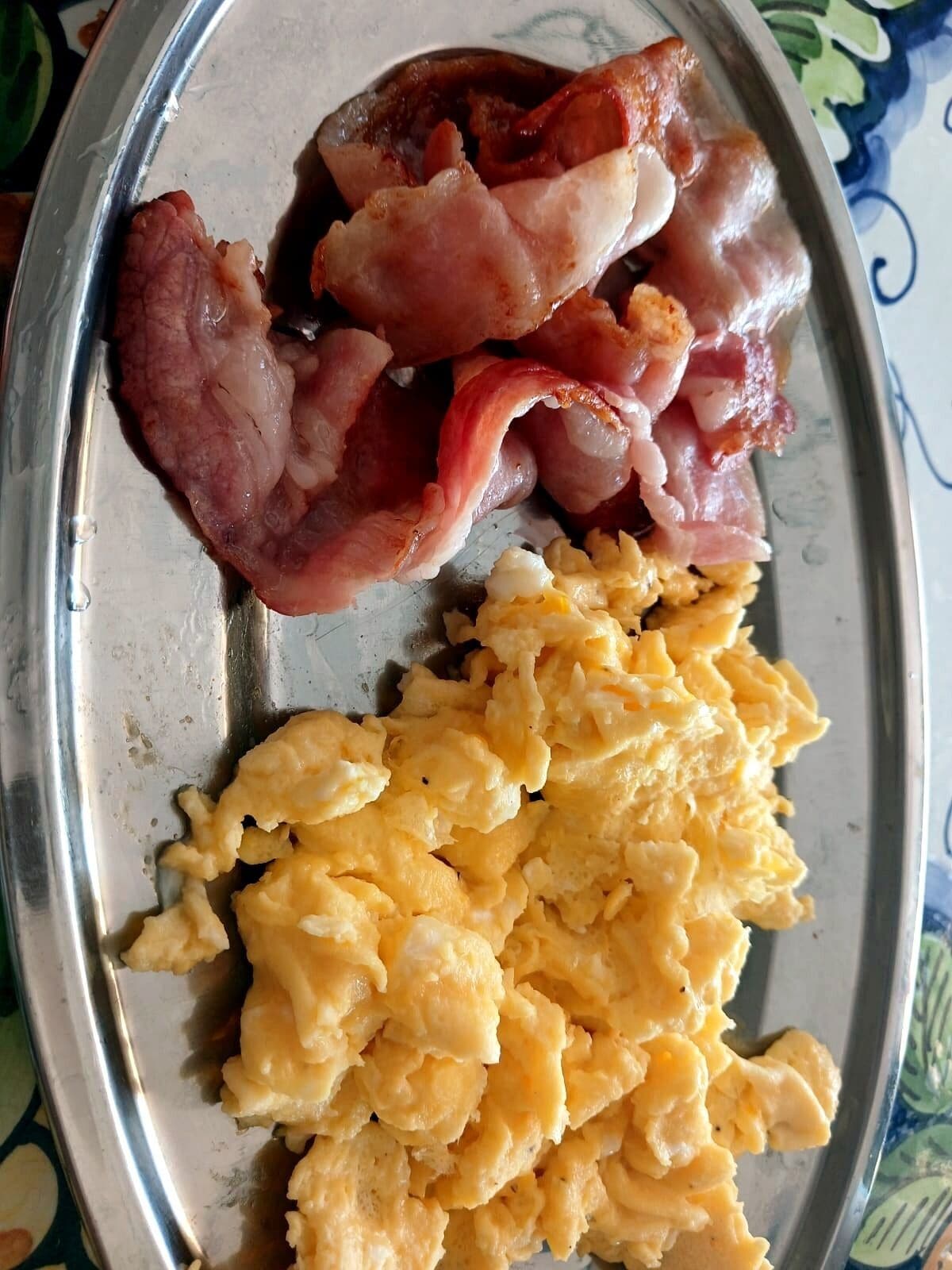 A plate with scrambled eggs and bacon.