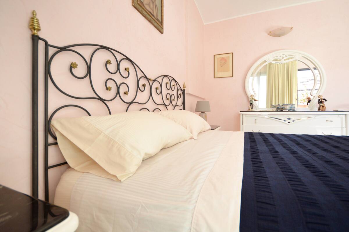 Un dormitorio con cama, cómoda, espejo y lámpara.