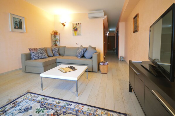 A living room with a sofa, a coffee table, a TV, and a fireplace.