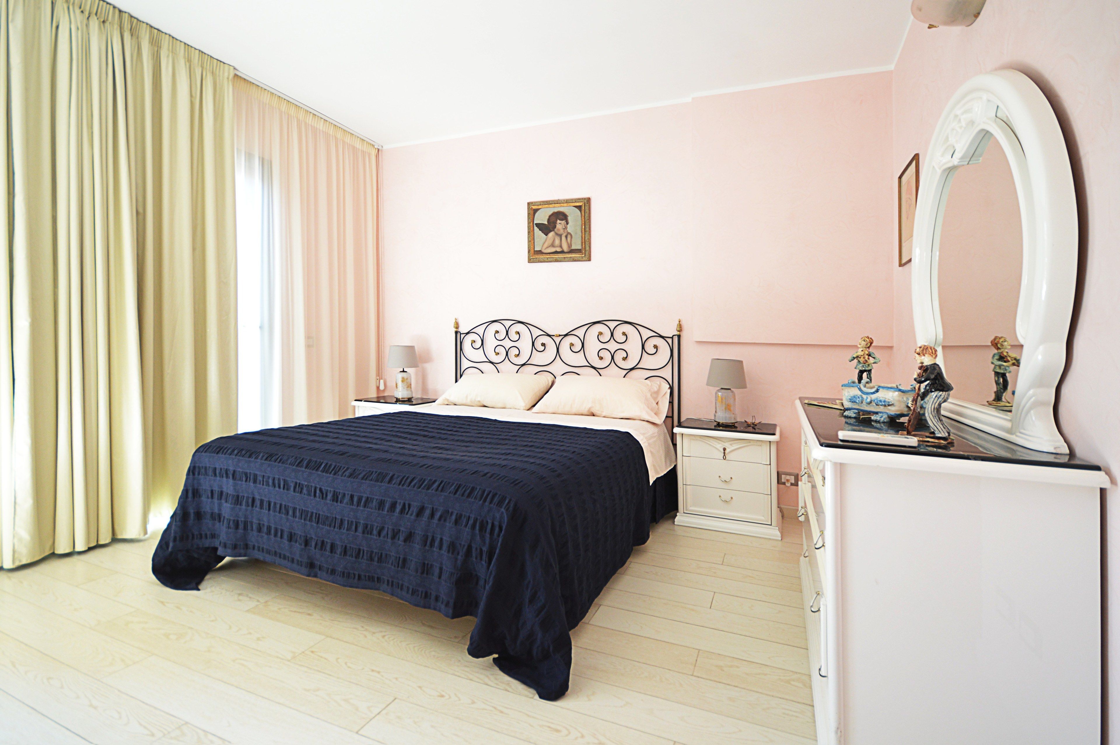 Ein Schlafzimmer mit Bett, Nachttischen, Kommode, Spiegel und einem Bild an der Wand.