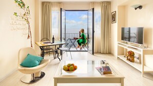 Un salon moderne avec balcon, un coin repas et un téléviseur.