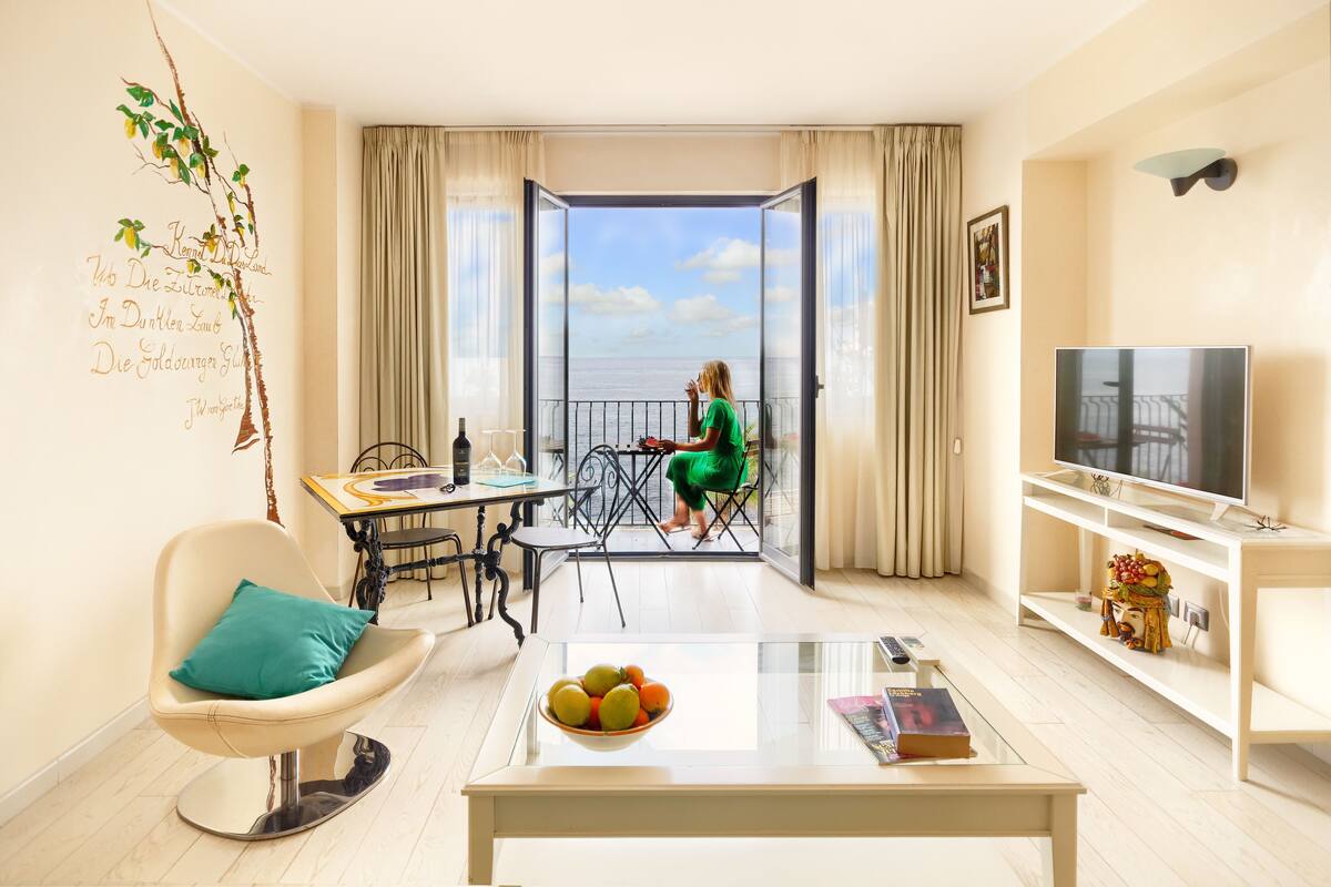 A modern living room with a balcony, a dining area, and a TV.