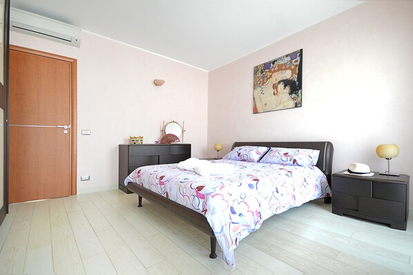 A bedroom with a bed, bedside tables, a dresser, a mirror, and a painting on the wall. - Mar Dei Poeti (Riposto)