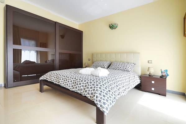A bedroom with a bed, a nightstand, a wall-mounted lamp, and a decorative item.