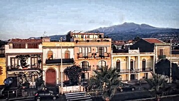 A row of traditional buildings with balconies, a street in front, and a mountain in the background.
