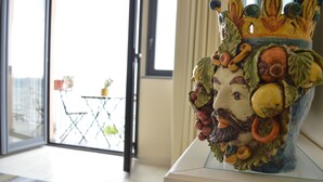 Un jarrón de cerámica con diseño floral sobre una mesa blanca en pedestal.