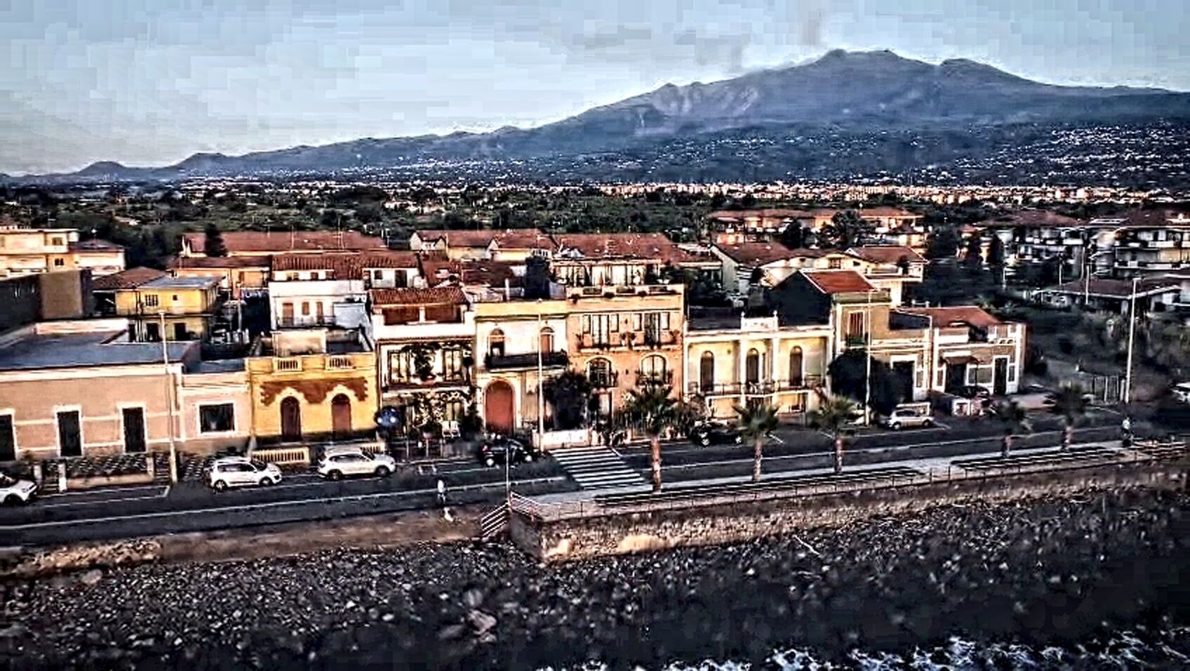 Eine Stadt mit Gebäuden, einer Straße und einem Berg im Hintergrund.