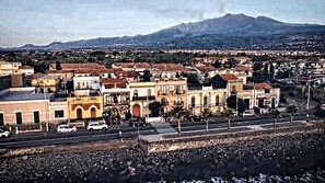 A town with buildings, a road, and a mountain in the background. - Mar Dei Poeti (Riposto)