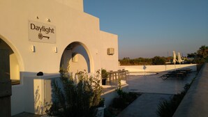 A building with a sign reading "Daylight" and a key symbol, featuring outdoor seating and a pool area. - Daylight (Santorini)