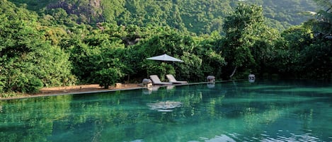 Una piscina al aire libre, sombrillas, tumbonas