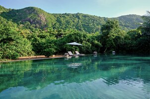 Una piscina al aire libre, sombrillas, tumbonas