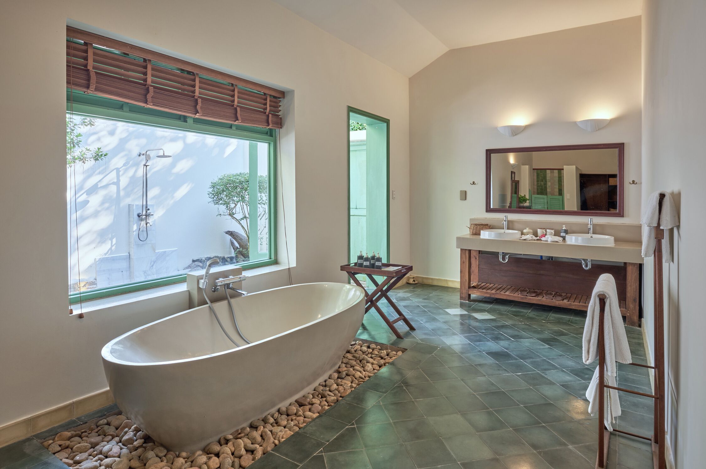 Une salle de bain moderne avec une baignoire sur pieds, une grande fenêtre et un meuble-lavabo avec un miroir.
