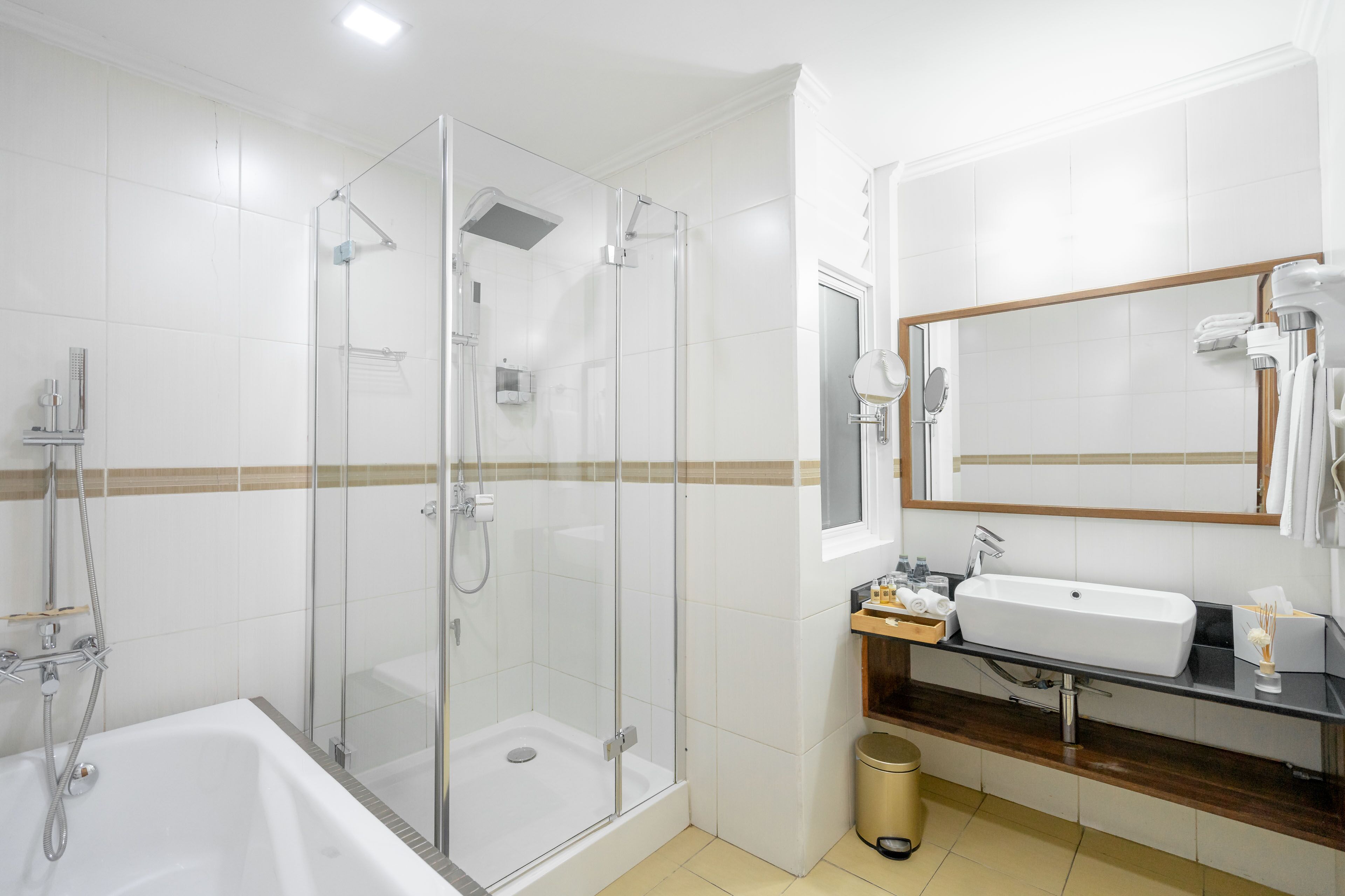 Un baño moderno con ducha de vidrio, una bañera blanca y un tocador con lavamanos y espejo.