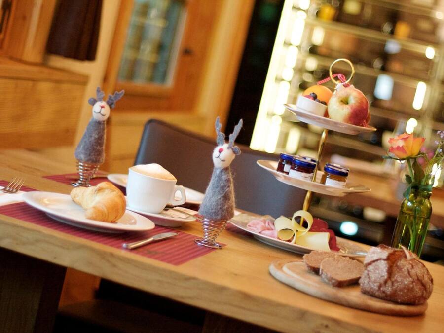 A dining table with croissants, a bowl of soup, and a tiered dessert stand with fruits and pastries.