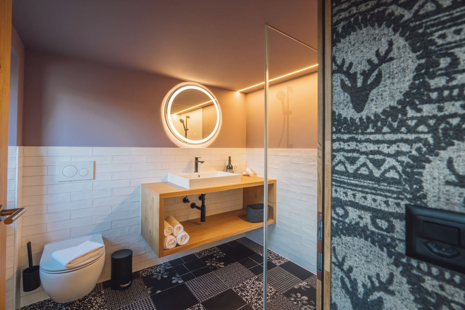 Un baño moderno con lavamanos blanco, tocador de madera y cabina de ducha de vidrio.
