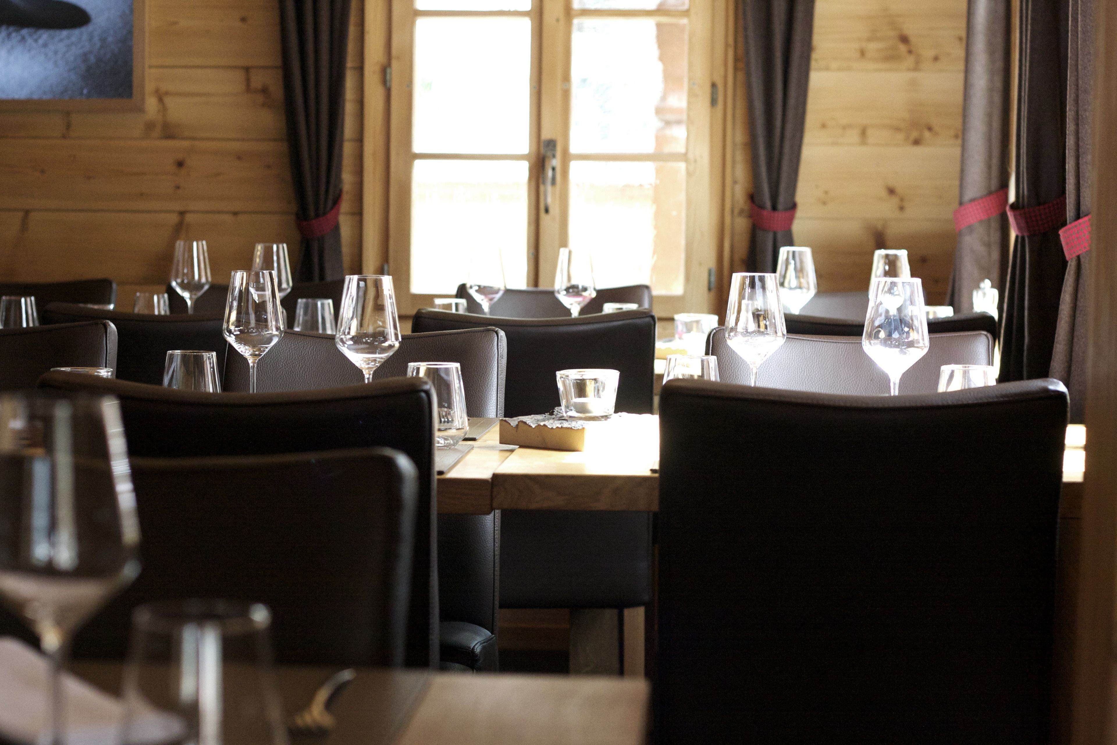 A dining area with tables set for service, chairs, and wine glasses.