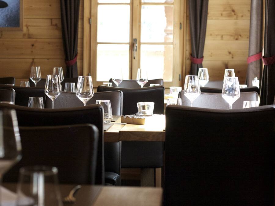 A dining area with tables set for service, chairs, and wine glasses.