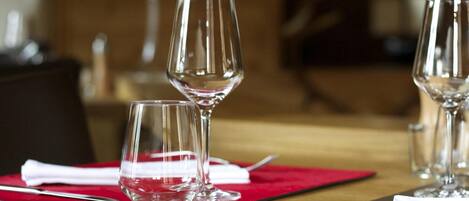 A dining table with three wine glasses and a fork on a red placemat.