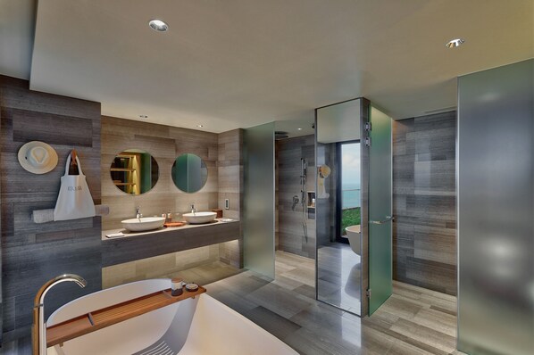 Un baño moderno con una bañera grande, dos lavamanos y una zona de ducha con mampara de vidrio.