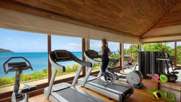 Un gimnasio con cintas de correr, equipamiento de ejercicio y vistas al océano.