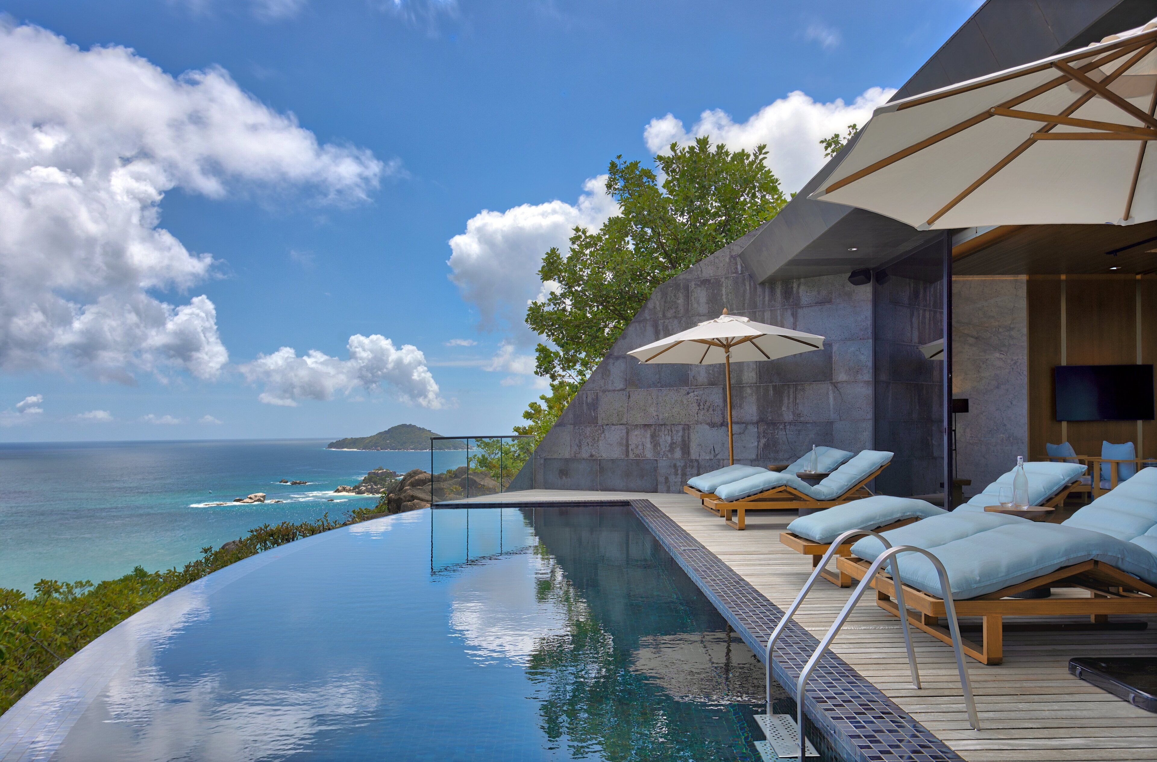 An infinity pool with a view of the ocean, lounge chairs, and umbrellas.
