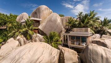 Ein Resort mit großen Felsformationen, Palmen und einem modernen Gebäude mit großen Fenstern.