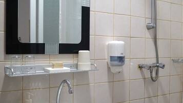 Un baño con lavabo, espejo, dispensador de jabón y ducha.