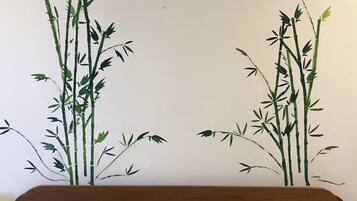 Een bed met twee kussens, een bruine plaid en een bloemenprint deken.