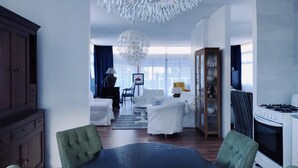 Un soggiorno moderno con zona pranzo, caratterizzato da un lampadario, divani e una cucina con piano cottura.