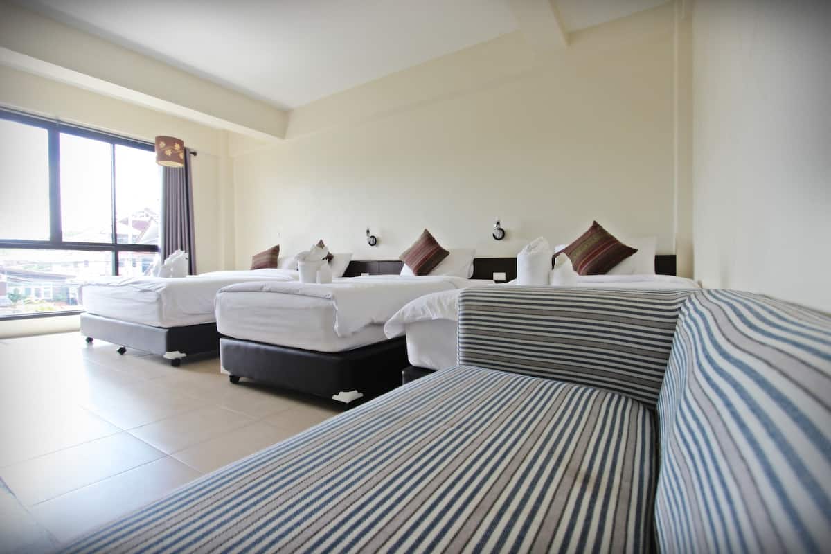 Quarto de hotel com duas camas, um sofá e uma janela grande com vista.
