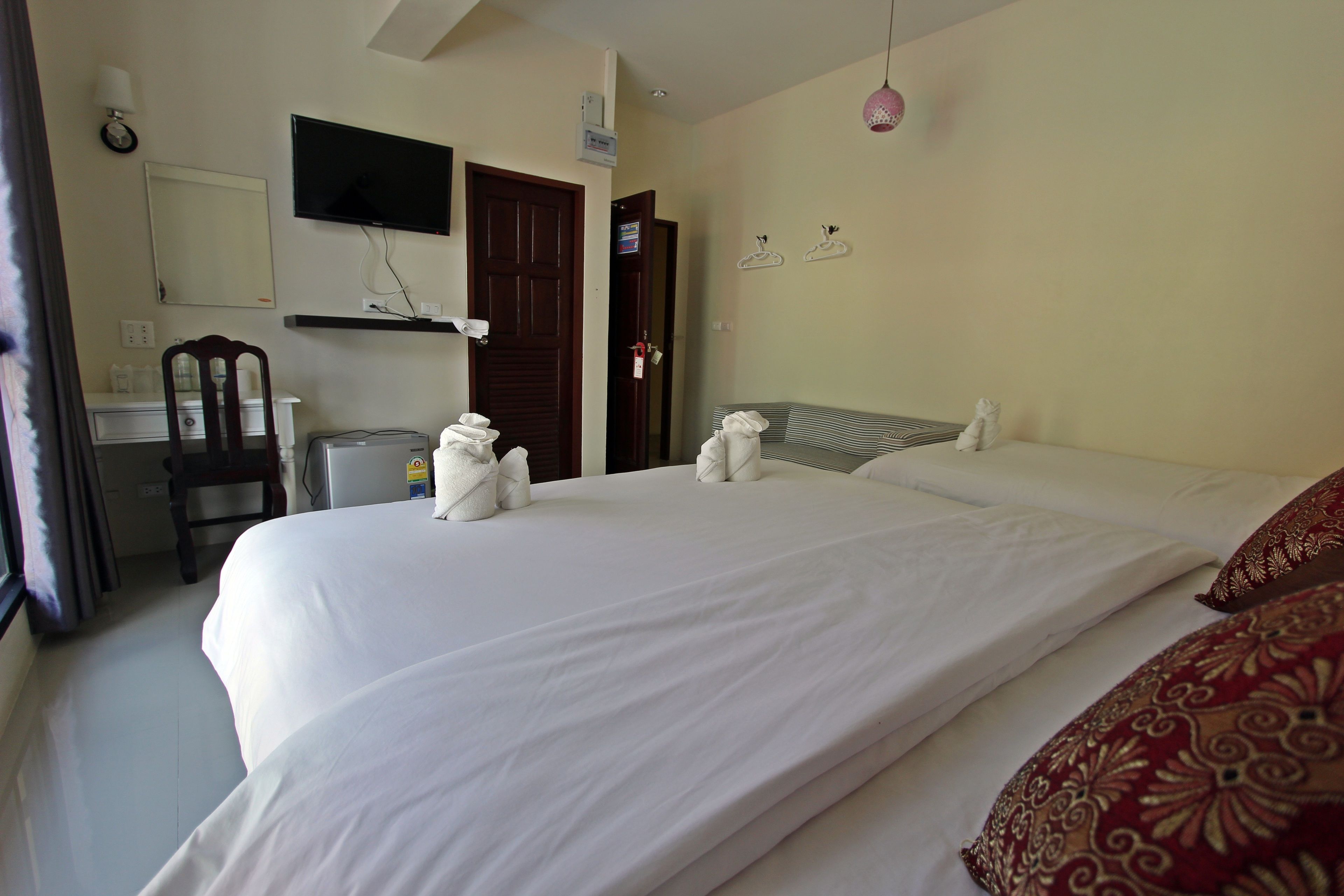 A hotel room with a large bed, a desk, a chair, a TV mounted on the wall, and a door.