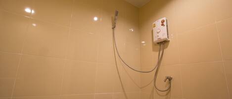 A bathroom with beige tiles, a showerhead, and a control panel.